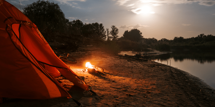 A tent set up by a river, surrounded by lush greenery, ideal for camping and adventure activities in Mudigere.