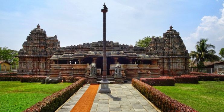 Belavadi Temple surrounded by lush green grass, showcasing intricate Hoysala-style carvings in a serene setting.