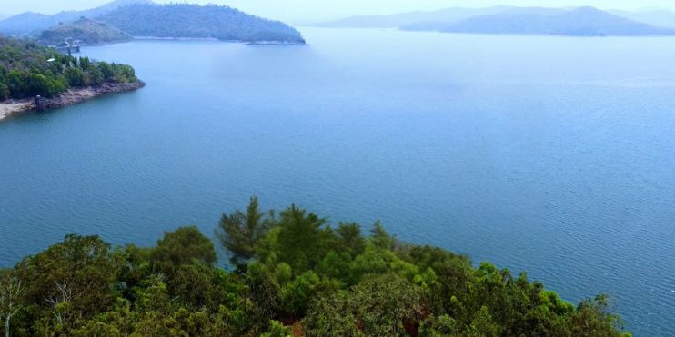 A serene view of the lake from a hilltop, surrounded by misty morning light, ideal for relaxation and nature appreciation.