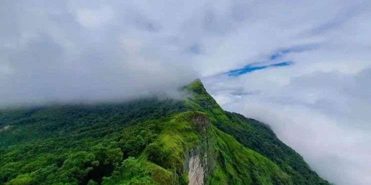 A mountain peak shrouded in clouds, symbolizing the historical significance of Rani Jhari in Karnataka's heritage.
