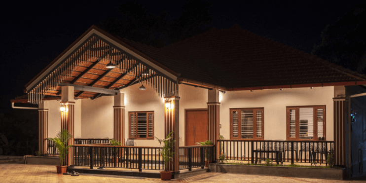 A cozy house illuminated at night, surrounded by nature, representing the tranquil Vanaba Hillview Homestay in Mudigere.