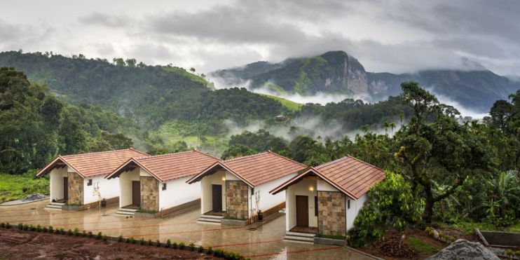 Three small cottages nestled in the mountains, surrounded by clouds, offering a serene retreat at Vanaba Hillview Homestay.