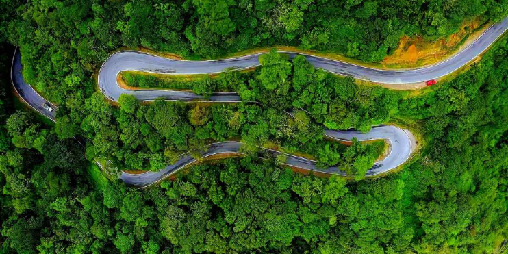 Aerial view of a winding road through a lush forest, showcasing the scenic beauty of Charmadi Ghat in Karnataka.
