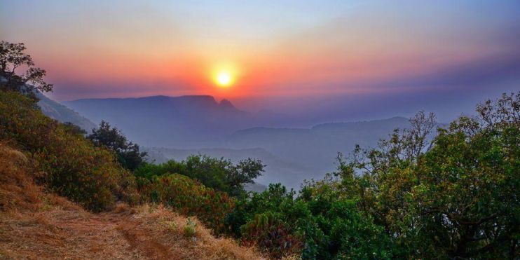 Sunset over misty mountains, capturing the serene beauty of hill stations in Karnataka during the monsoon season.