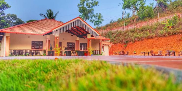 A charming homestay building surrounded by coffee plantations and misty hills in Mudigere, inviting guests to reconnect with nature.