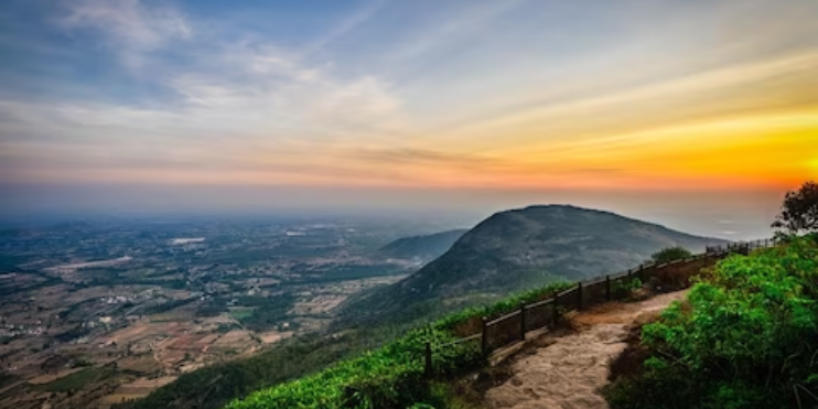 Sunset over lush hills in Kodagu, Karnataka, India, showcasing vibrant colors and serene natural beauty during monsoon.