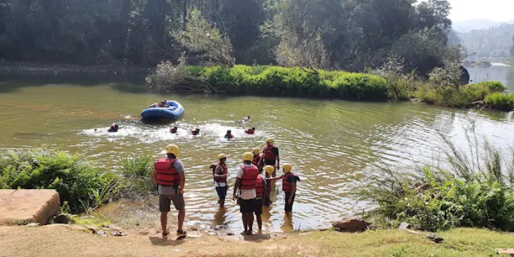 A group of people enjoying white-water rafting on the Bhadra River, surrounded by lush forest scenery.