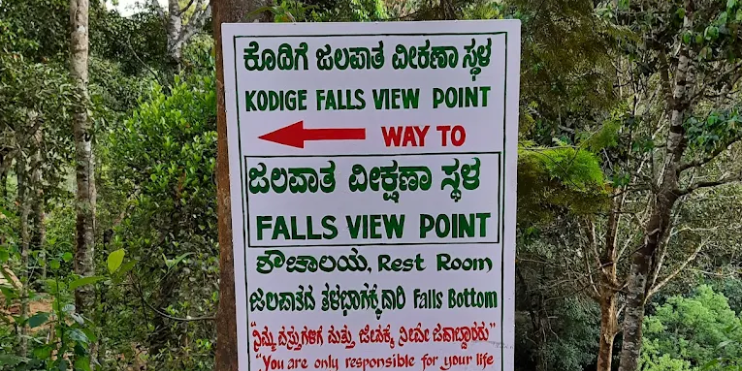 Sign directing visitors to Kodige Falls, highlighting the scenic route and adventure of reaching this natural attraction.
