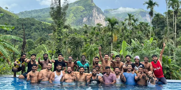 A group of men enjoying a swim in a pool, with scenic mountains visible in the background at Vanaba Hillview.