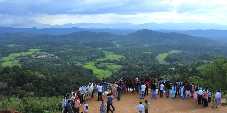 A group of people stands on a hill, gazing at a lush valley below, surrounded by rolling hills and scenic beauty.